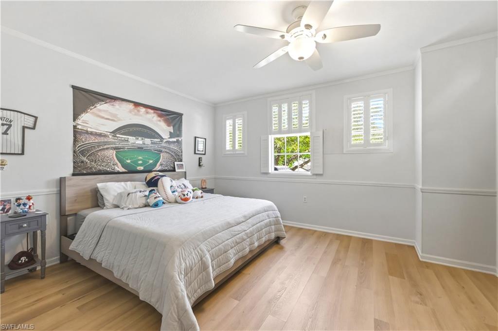 Bedroom with crown molding, light wood-style floors, and ceiling fan