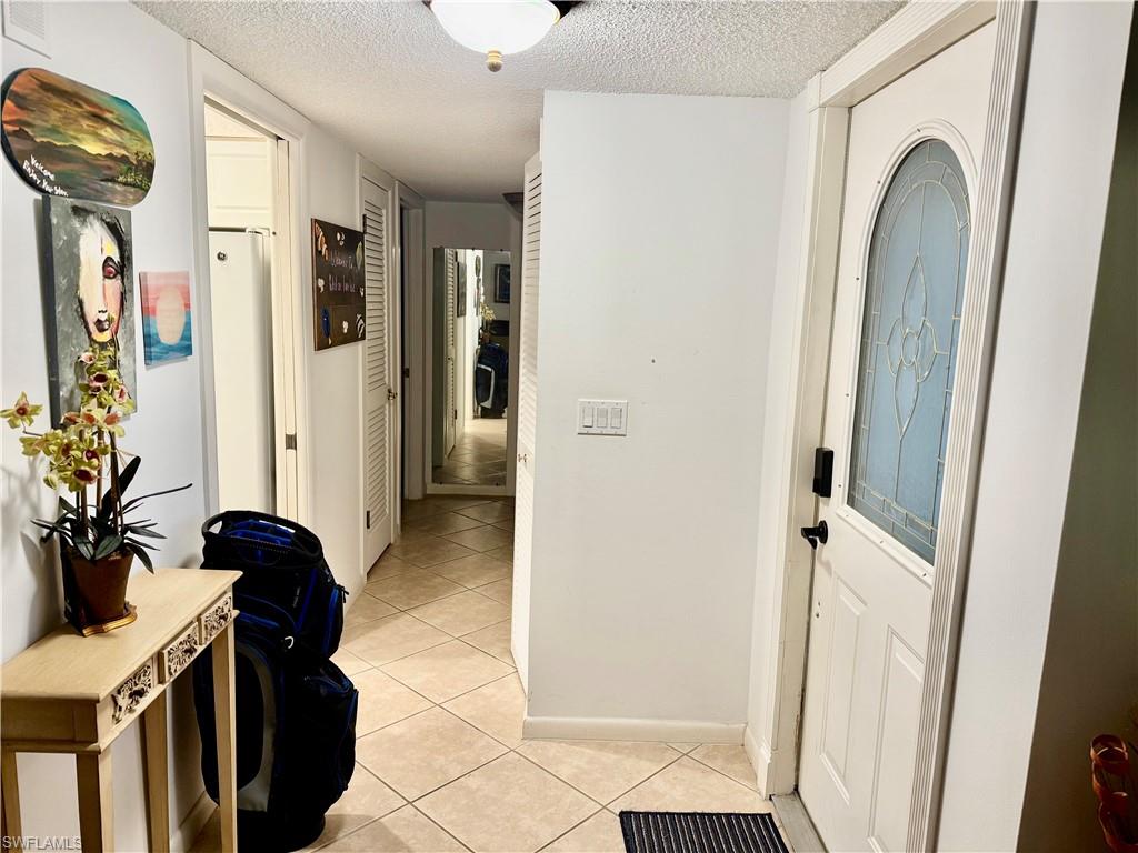 Hallway featuring a textured ceiling and light tile patterned flooring