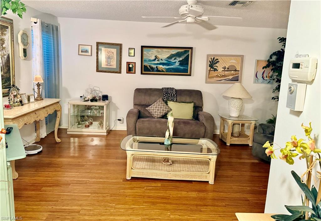 Living area featuring wood finished floors, a textured ceiling, and a ceiling fan