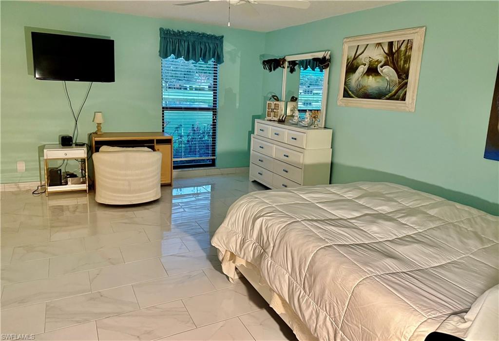 Bedroom with ceiling fan and light marble finish floors