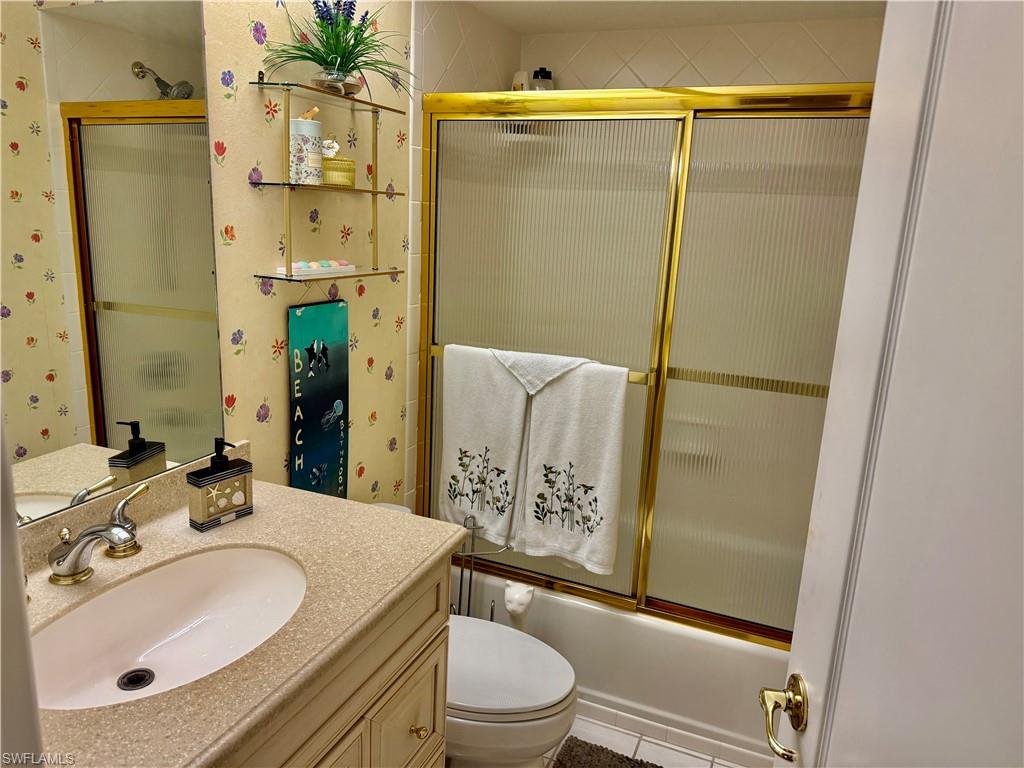Full bath with vanity, combined bath / shower with glass door, and wallpapered walls
