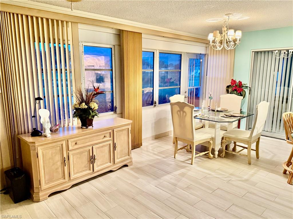 Dining room with a textured ceiling, light wood-style flooring, and a chandelier