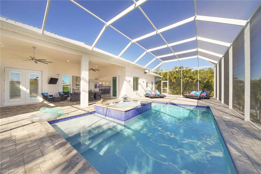 Integrated pool / hot tub featuring a sunroom, a patio area, french doors, glass enclosure, and outdoor furniture
