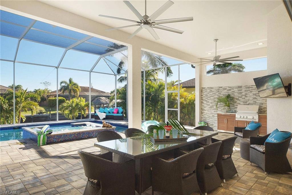 View of patio / terrace with a pool with connected hot tub, a lanai, a sunroom, ceiling fan, and an outdoor kitchen / dining area