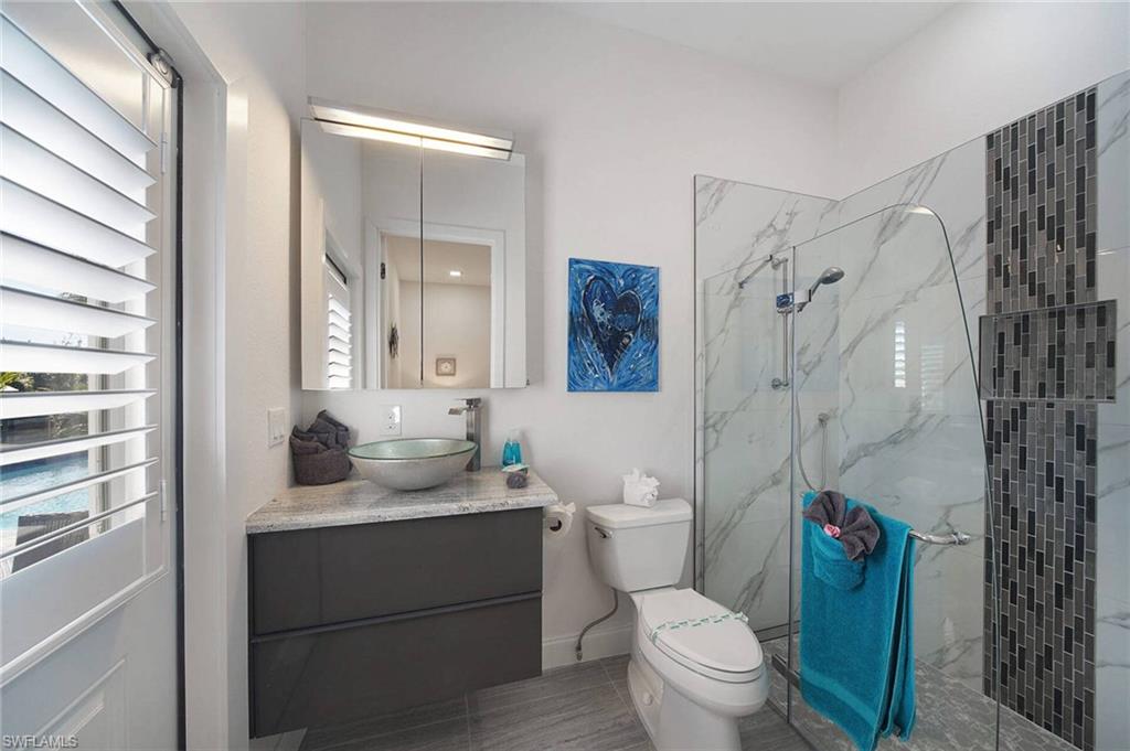 Bathroom with vanity, a marble finish shower, and light tile patterned floors
