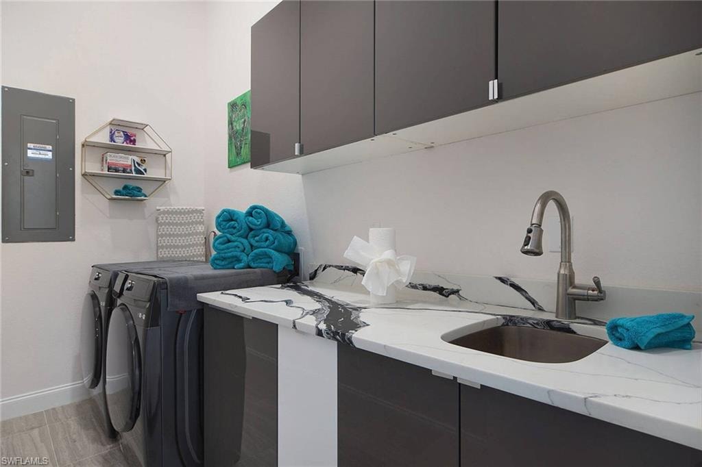 Laundry room featuring electric panel, independent washer and dryer, and cabinet space