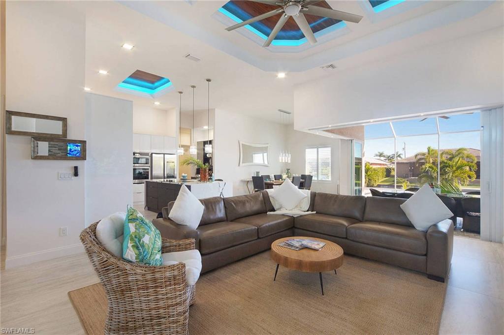 Living area featuring a high tray ceiling, a ceiling fan, and recessed lighting