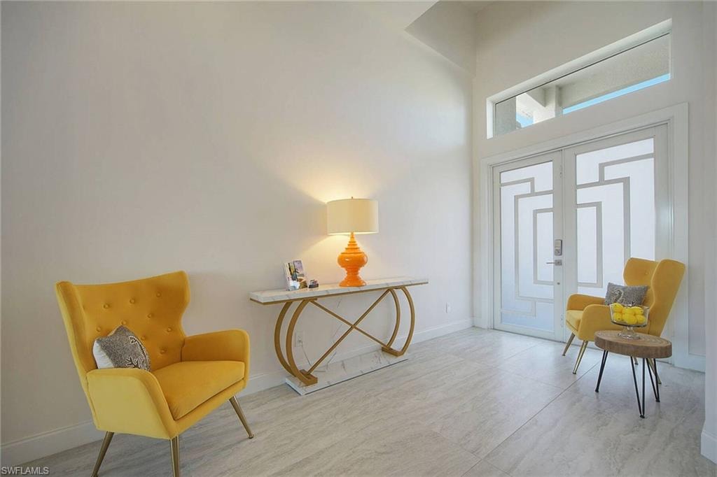 Sitting room featuring a high ceiling and baseboards