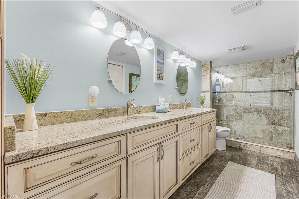 The primary bathroom has a raised vanity with a granite countertop with dual sinks, a spacious shower, a walk-in closet and a linen closet.