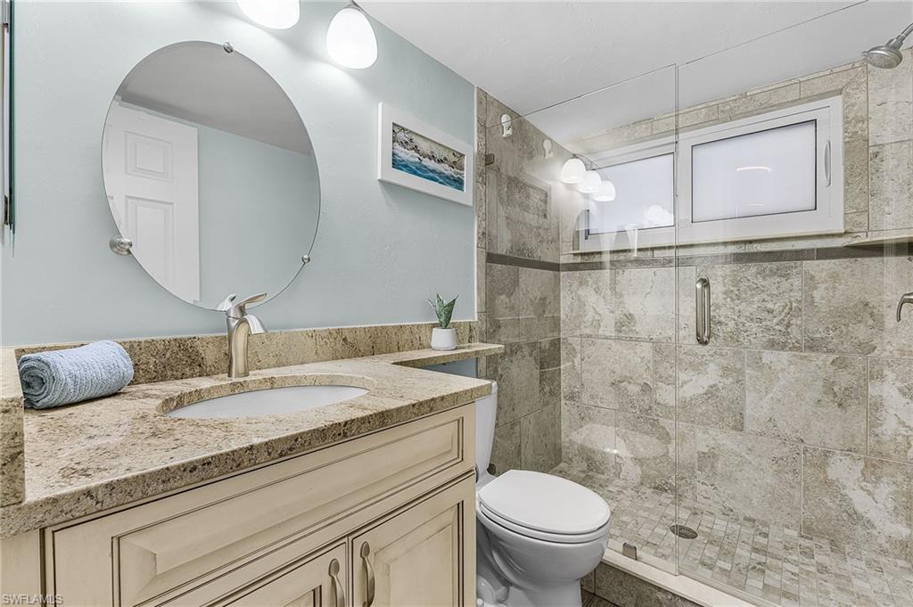 Guest bathroom with raised vanity, granite countertop and tiled shower.