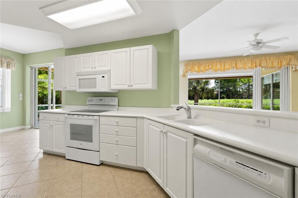 White and bright kitchen features eat in area and breakfast bar