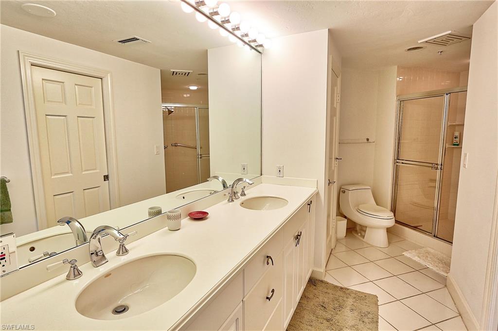 Bathroom featuring toilet, tile patterned flooring, a sink, and a stall shower