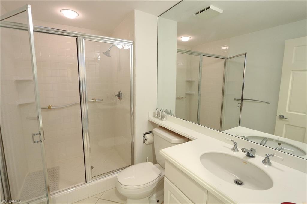 Bathroom with tile patterned flooring, visible vents, toilet, vanity, and a stall shower