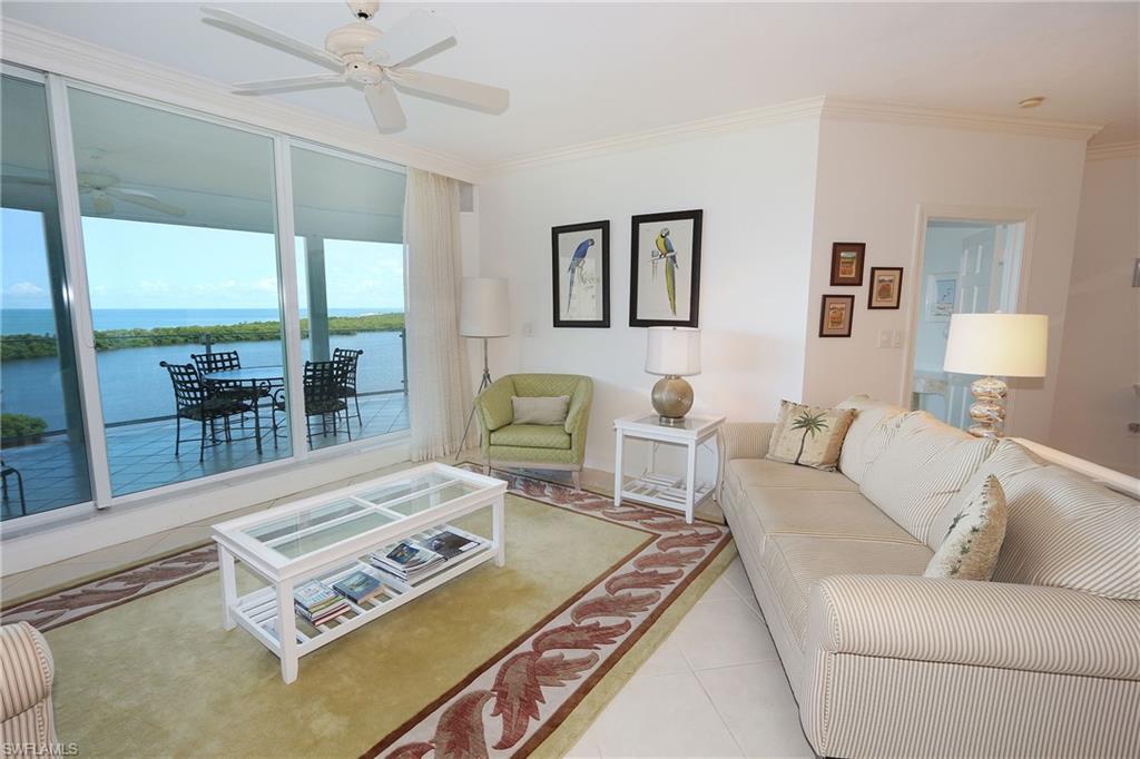Tiled living area with ceiling fan, a water view, and ornamental molding