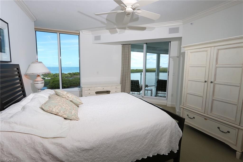 Bedroom featuring multiple windows, ornamental molding, access to outside, and a water view