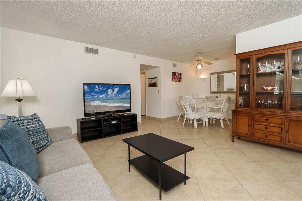 Living area with ceiling fan, light tile patterned flooring, and a textured ceiling