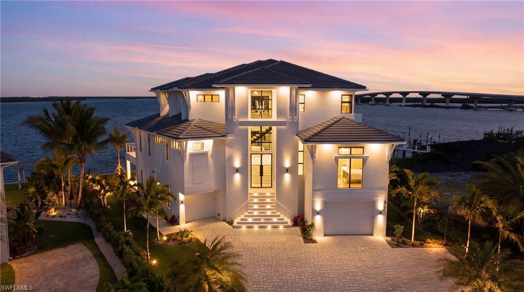Modern home featuring an attached garage, a tile roof, driveway, and stucco siding - Virtually Edited Image