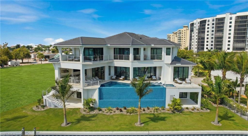 Back of house featuring a balcony, a patio, a yard, and an outdoor pool - Virtually Edited Image