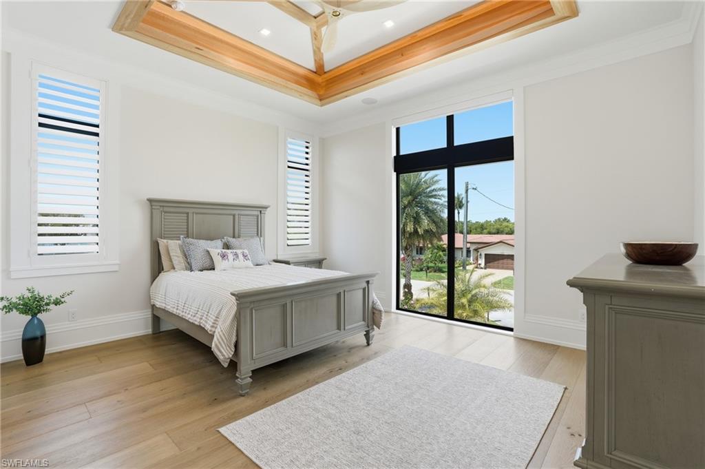 Bedroom with light wood-type flooring and crown molding - Virtually Edited Image
