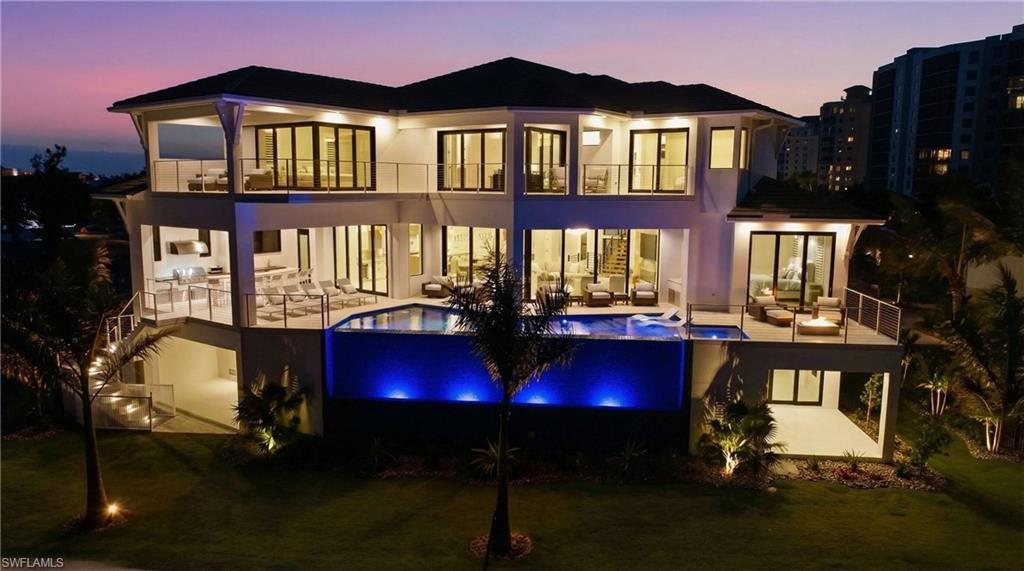 Rear view of house with an infinity pool, a balcony, a yard, and an outdoor lounge area - Virtually Edited Image