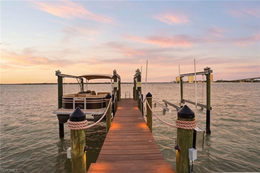 Dock area featuring boat lift and a water view - Virtually Edited Image