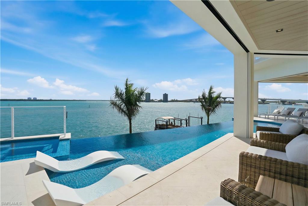View of swimming pool with an infinity pool, a water view, and patio surround - Virtually Edited Image