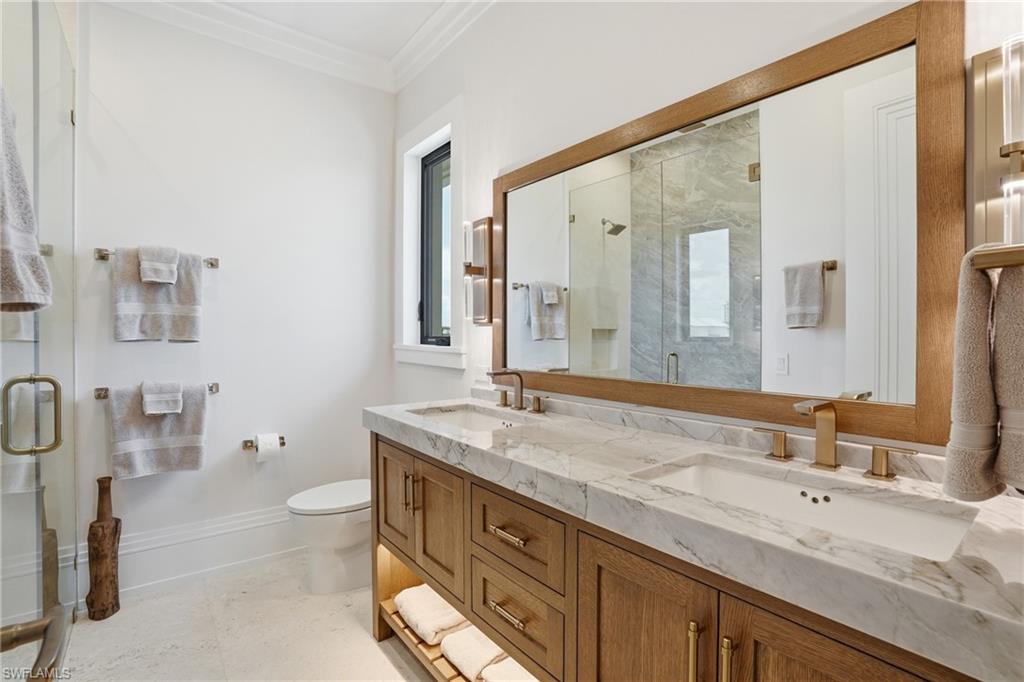 Bathroom featuring a shower stall, crown molding, and double vanity - Virtually Edited Image