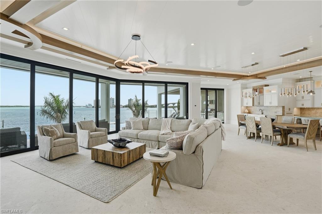 Living area featuring hanging lights, a water view, and a raised ceiling - Virtually Edited Image