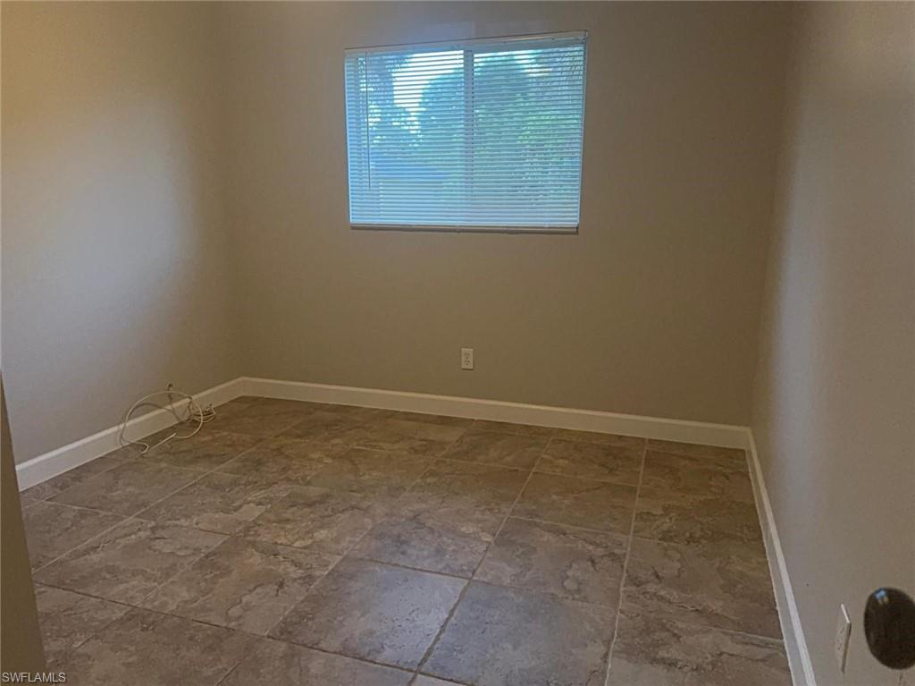 Room featuring neutral wall paint, tiled flooring, a single window with blinds, and white baseboards