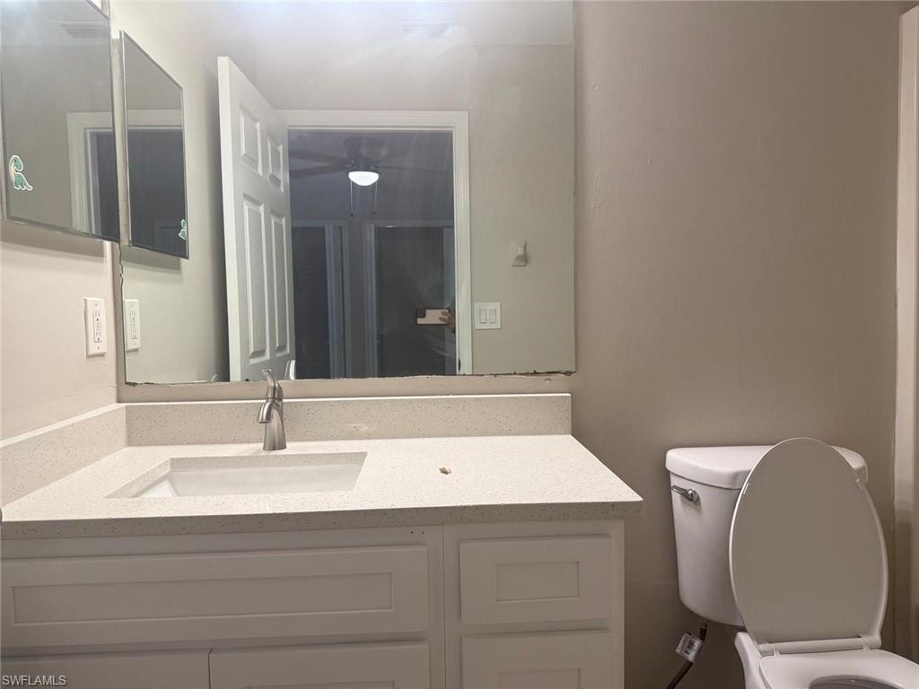Bathroom vanity featuring white cabinetry, an integrated sink, a speckled countertop, and a single-handle faucet