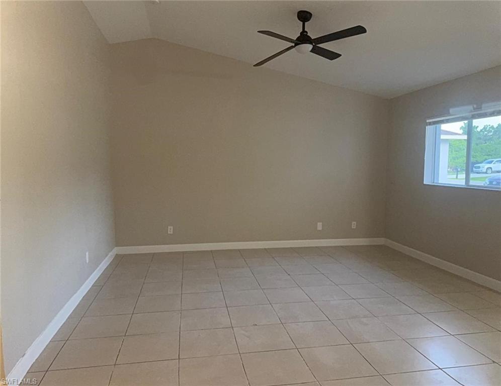 Spacious room featuring vaulted ceilings, neutral-toned walls, tiled flooring, a contemporary ceiling fan, and a large window
