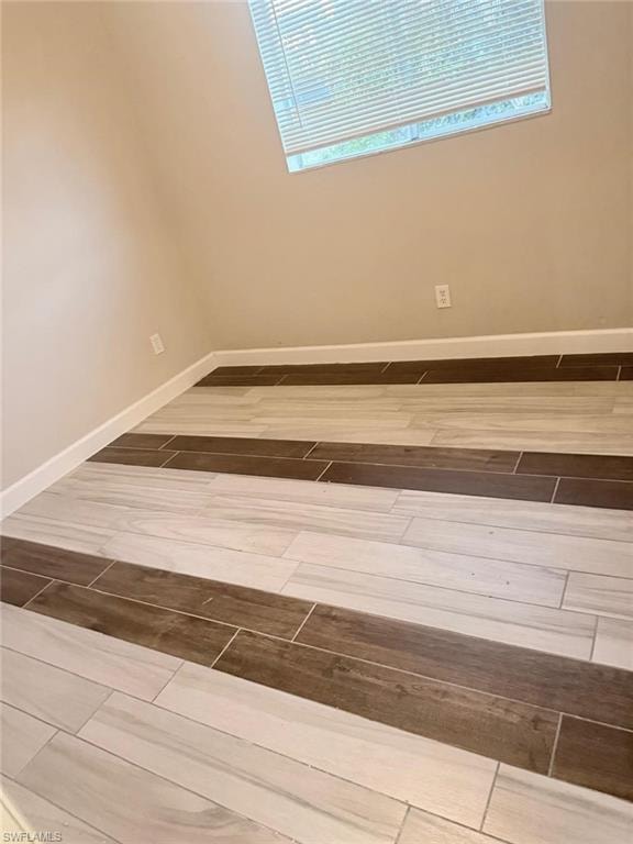Ceramic tile flooring with alternating light and dark wood-look planks, neutral wall color, and white baseboards