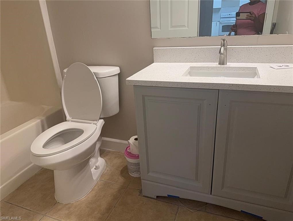 Bathroom featuring a white vanity with paneling, a light-colored speckled countertop, an integrated rectangular sink, and a brushed nickel faucet