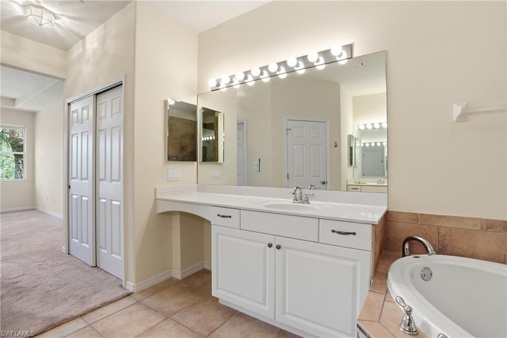 Bathroom with vanity, light carpet, light tile patterned floors, and a garden tub