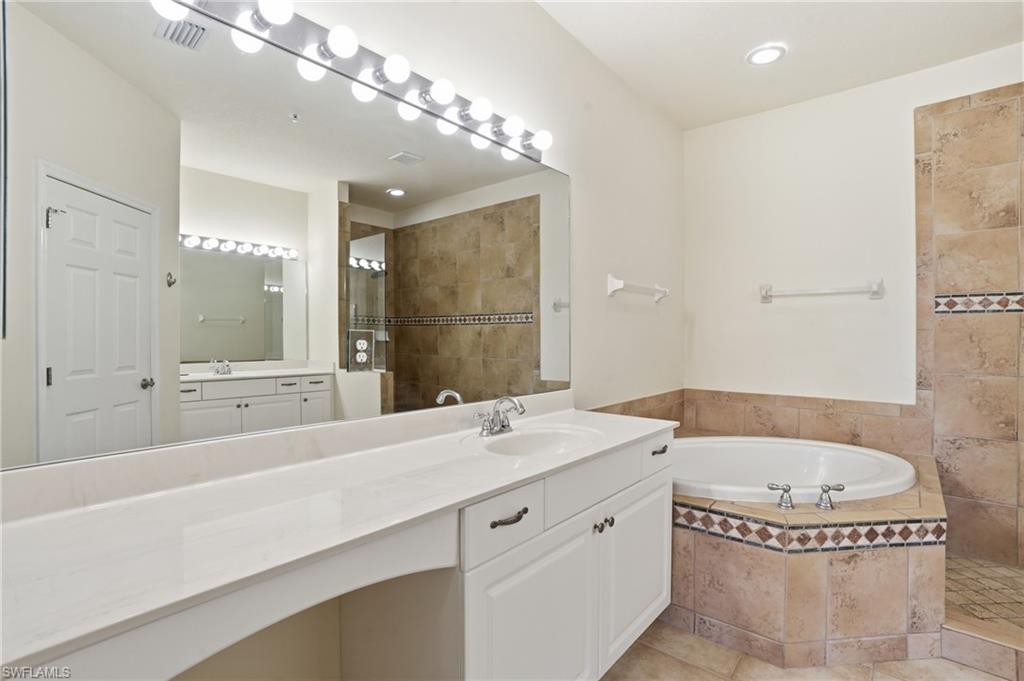 Full bathroom with a walk in shower, vanity, a garden tub, and light tile patterned floors