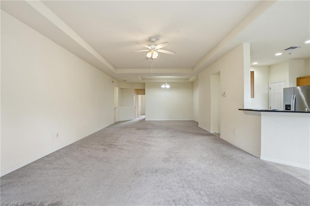 Unfurnished living room featuring ceiling fan, light colored carpet, a raised ceiling, and recessed lighting