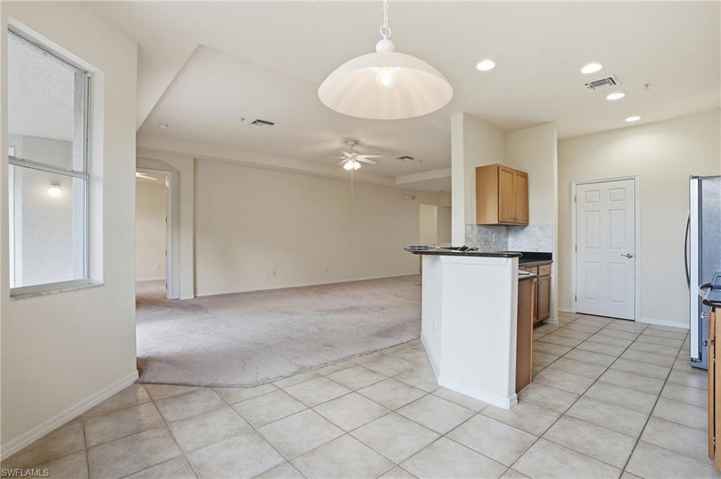 Kitchen featuring light carpet, decorative light fixtures, open floor plan, ceiling fan, and a peninsula