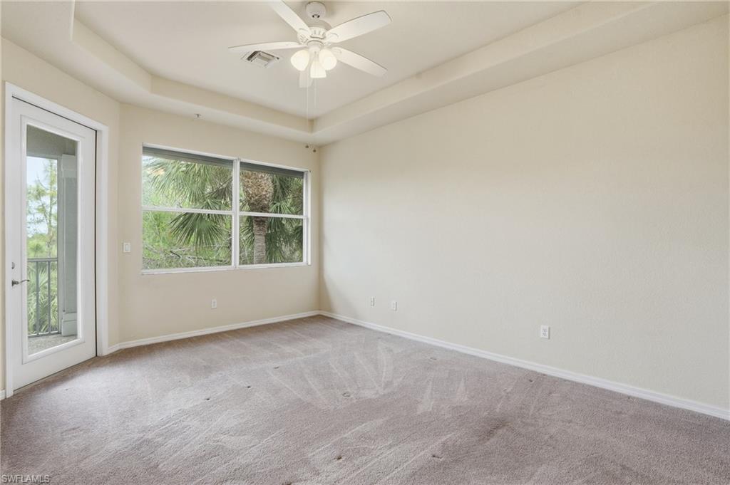 Unfurnished room with a tray ceiling, carpet flooring, and a ceiling fan