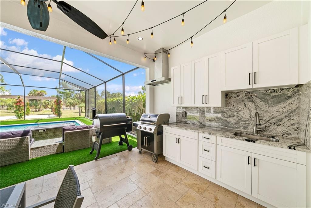 View of patio / terrace with an outdoor pool, a sunroom, a lanai, and an outdoor kitchen