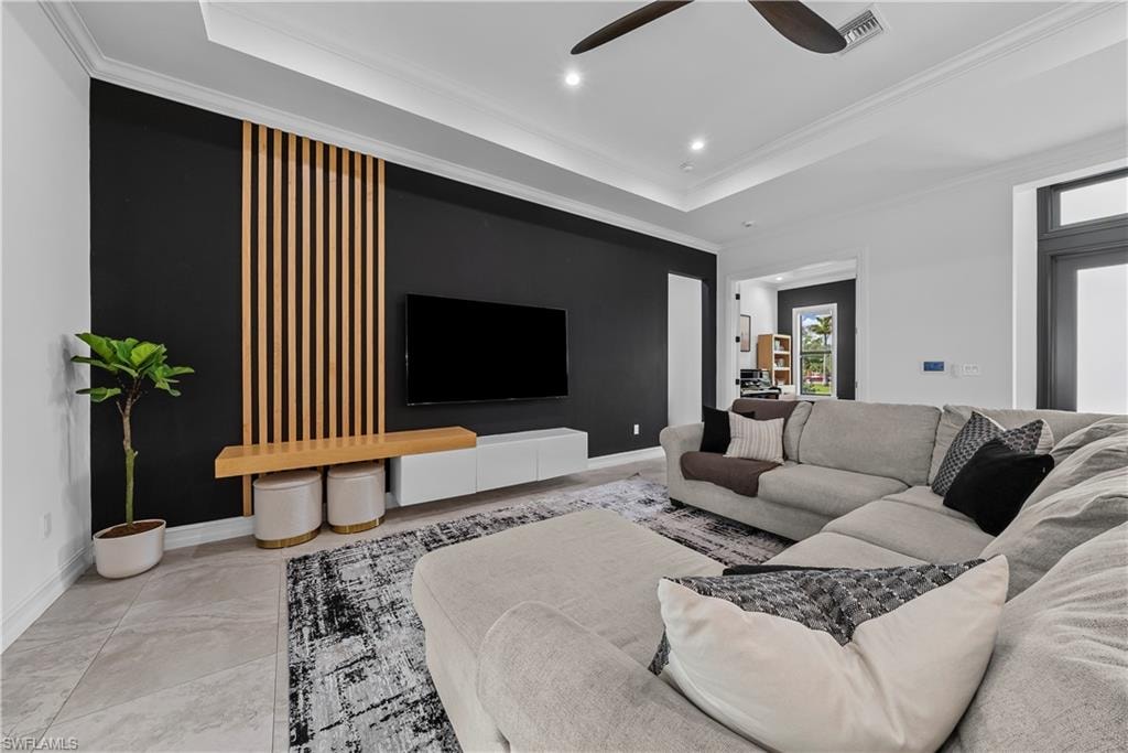Living room featuring ornamental molding, a ceiling fan, recessed lighting, and a raised ceiling