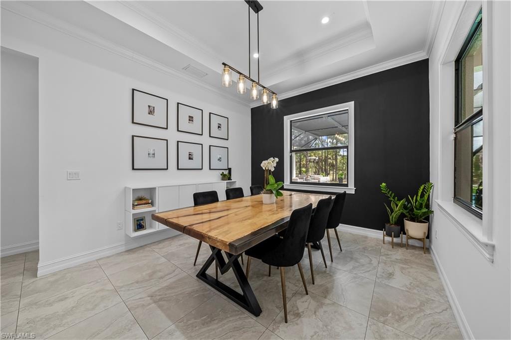 Dining area with crown molding, a raised ceiling, and light marble finish flooring