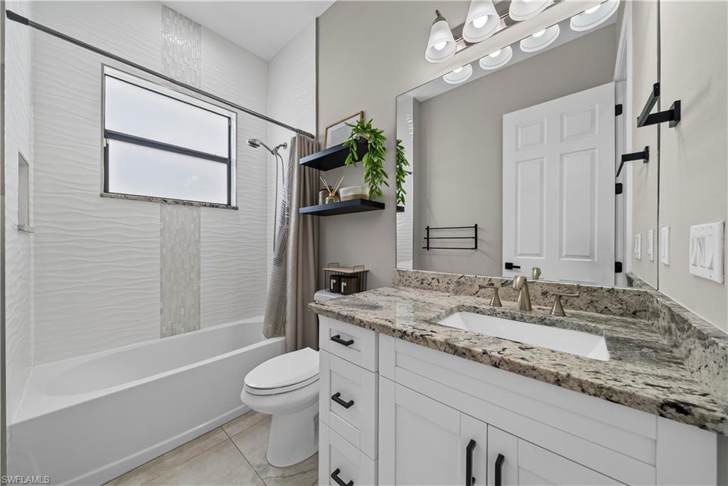 Bathroom with vanity, shower / bath combo with shower curtain, and light tile patterned floors