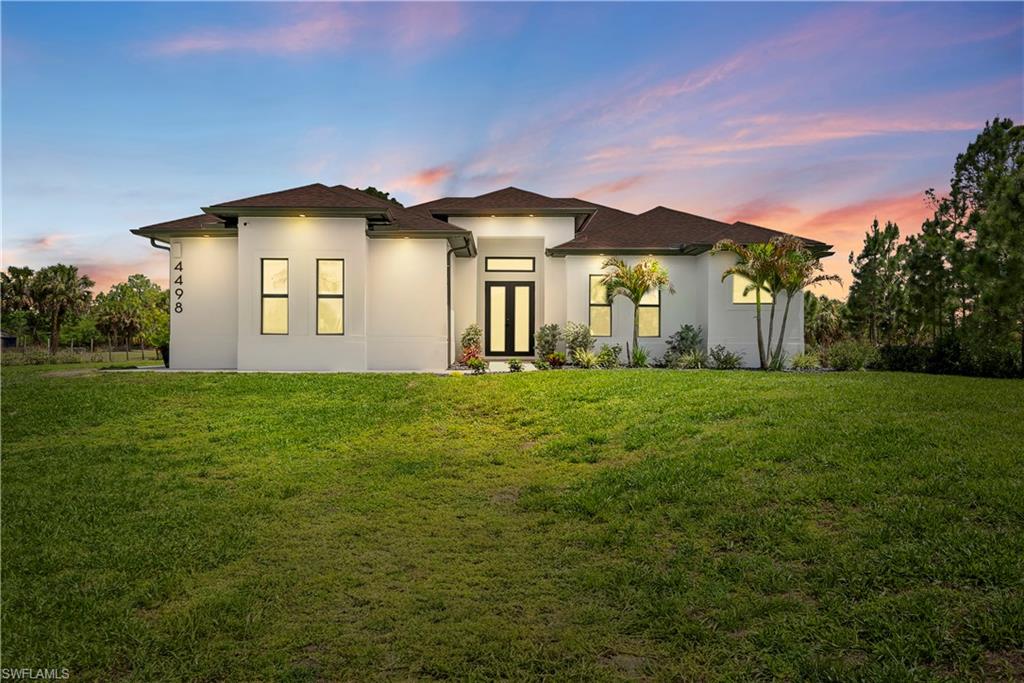 View of front facade featuring stucco siding and a lawn
