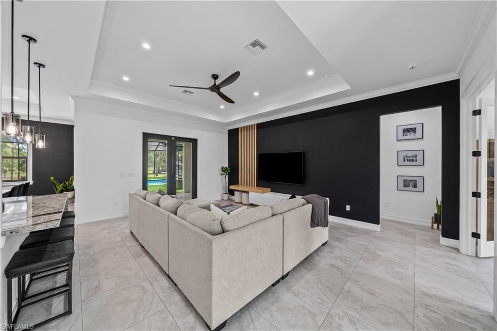 Living room featuring ornamental molding, ceiling fan, a raised ceiling, and recessed lighting