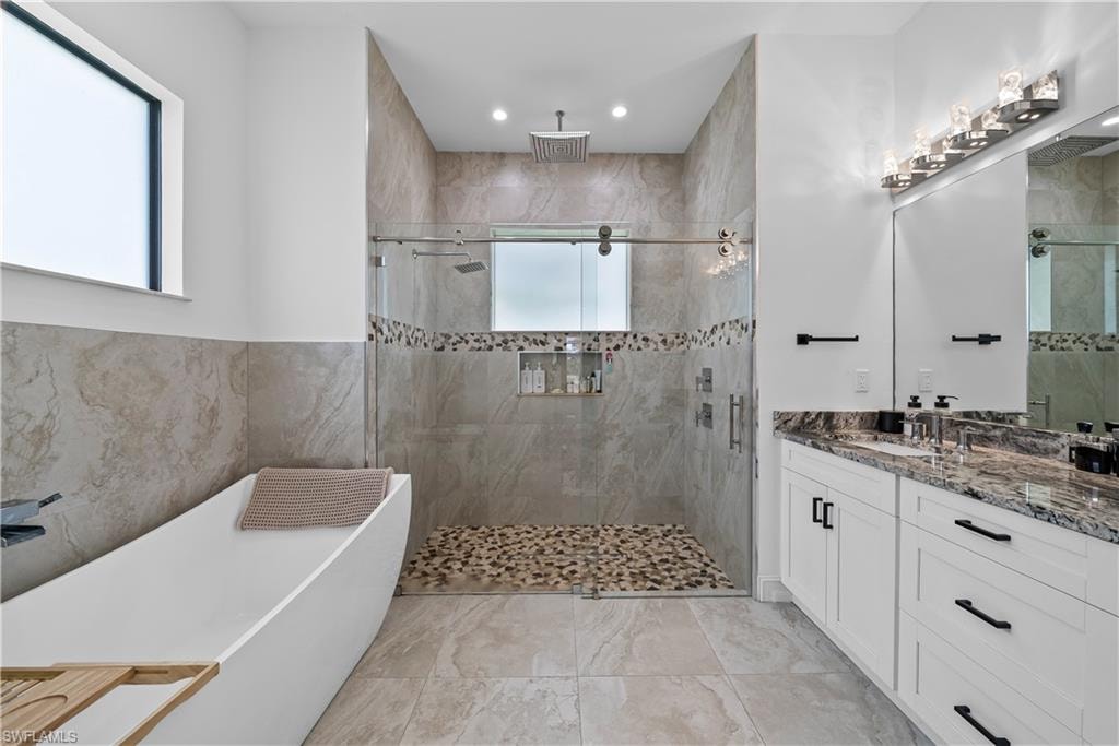 Full bathroom featuring a soaking tub, vanity, a shower stall, and recessed lighting