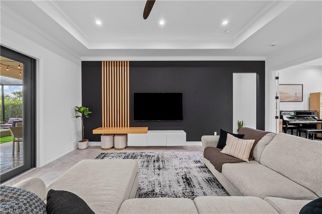 Living area featuring ceiling fan, a tray ceiling, and crown molding