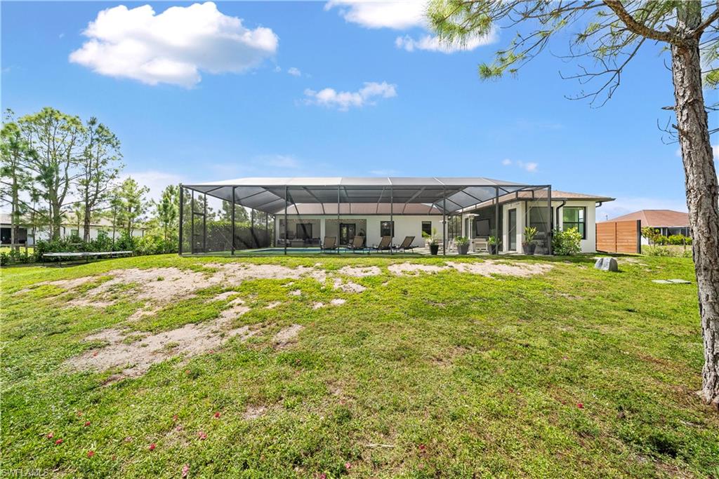 Back of property featuring glass enclosure, a sunroom, and a lawn