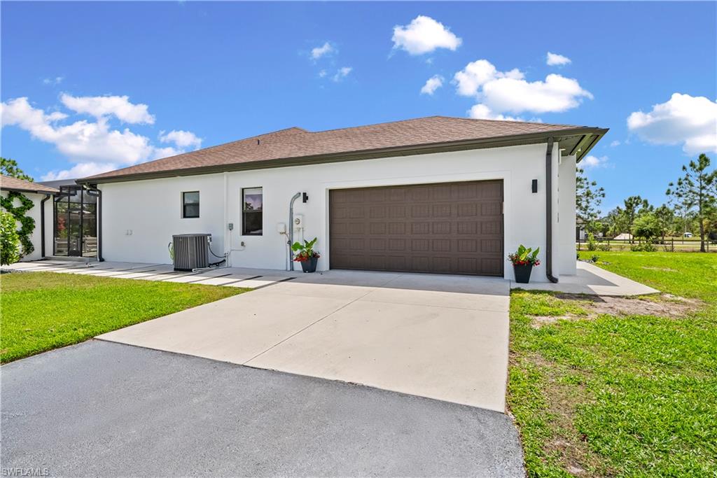 View of front of property with a front lawn, stucco siding, concrete driveway, and an attached garage