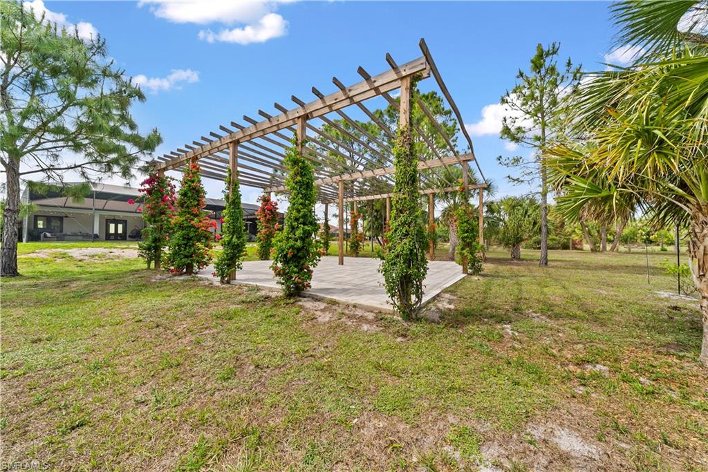 View of grassy yard featuring a pergola and a patio