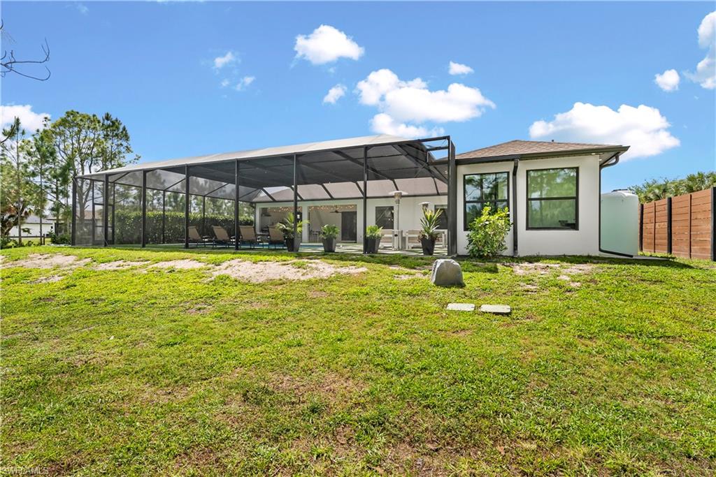 Back of property with glass enclosure, a sunroom, a yard, and stucco siding